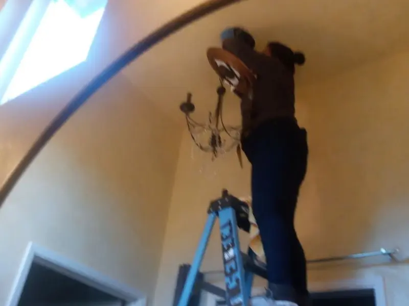 Electrician installing a chandelier in a Gorham residence